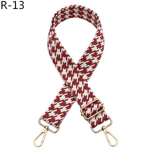 Detail of red houndstooth woven bag strap with adjustable light gold metal buckles