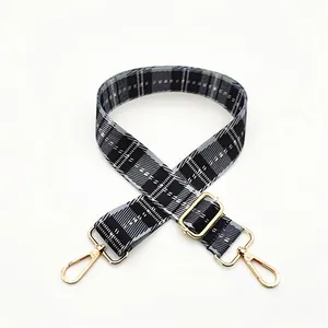 Detail view of black and white checkered woven strap with adjustable gold lobster clasps