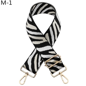 Detail of zebra pattern woven bag strap with golden metal hooks and adjustable buckle