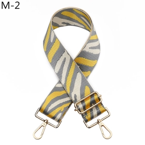 Macro view of adjustable wide striped strap with yellow zebra pattern and gold metal hooks