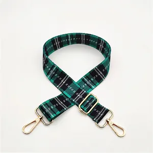 Detail view of adjustable green and black plaid strap with gold metal lobster clasps
