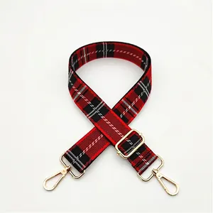 Detail view of adjustable red and black plaid bag strap with gold metal hooks