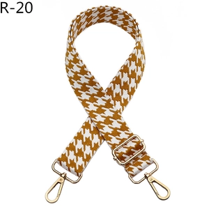 Detail of adjustable houndstooth bag strap with gold metal hooks and yellow jacquard weave
