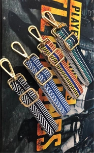 Détail de bandoulières réglables avec boucles dorées et quatre motifs géométriques