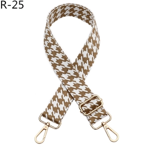 Detail view of houndstooth woven shoulder strap with gold metal buckle and lobster hooks