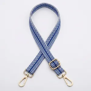 Détail de la bandoulière jacquard réglable avec motifs géométriques bleu et blanc et clips dorés