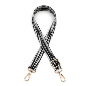 Détail d'une bandoulière jacquard réglable avec motifs noir et blanc et ferrures dorées