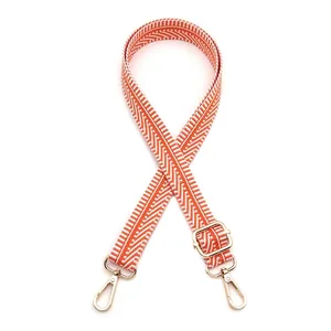 Détail de la bandoulière de sac en jacquard orange et blanc avec crochets dorés réglables