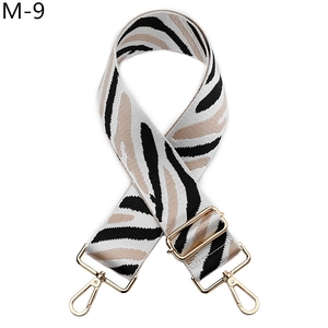 Detail of adjustable zebra pattern woven shoulder strap with gold metal lobster clasps