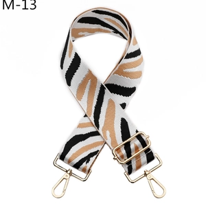 Detail of adjustable zebra stripe canvas bag strap with luxury gold metal hooks