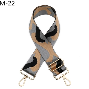 Detailed view of adjustable wide jacquard bag strap with camo pattern and gold buckles