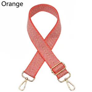 Detail view of orange chevron woven adjustable bag strap with golden metal lobster clasps