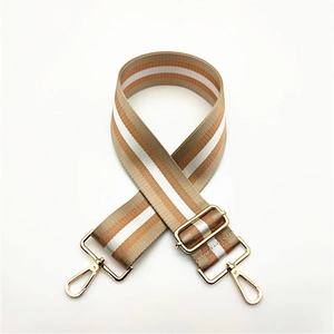 Detail view of adjustable striped bag strap with gold metal hooks and coffee-white tones
