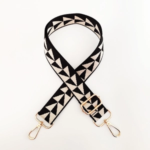 Detail of wide woven bag strap with geometric ethnic pattern and gold metal buckles