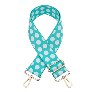 Close-up of teal polka dot woven bag strap with golden metal hardware and adjuster