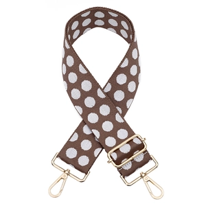 Close-up of adjustable brown polka dot bag strap with premium gold metal hardware