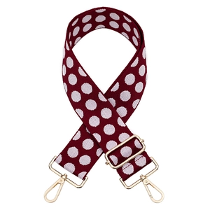 Close-up of red-brown polka dot thick jacquard strap with gold-tone metal hardware