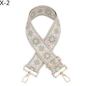 Detail of ethnic jacquard strap with floral embroidery and golden adjustable buckles