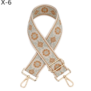 Detail of floral jacquard bag strap with orange daisy patterns and golden metal hardware