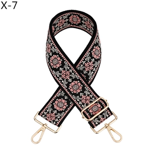 Detail of pink floral embroidery on black webbing strap with golden swivel snap hooks
