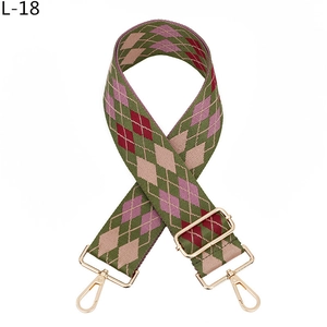 Macro detail of adjustable woven bag strap with green pink argyle pattern and gold buckle