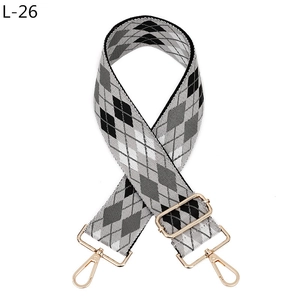 Close-up of argyle patterned woven bag strap with adjustable light gold metal hardware