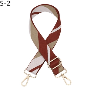 Detail of adjustable woven canvas bag strap with brown geometric patterns and gold hooks