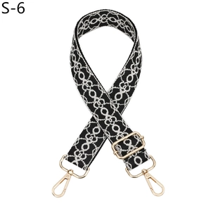 Close-up of black and white geometric jacquard bag strap with gold metal hooks and slider