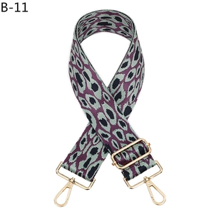 Close-up of leopard pattern purple green woven shoulder strap with gold metal hooks