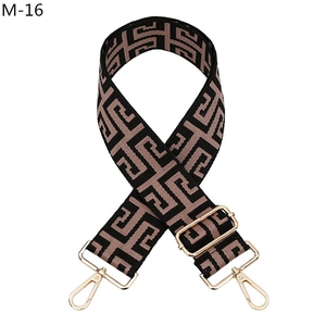 Detail of jacquard woven geometric strap with pale gold metal swivel hooks and adjuster