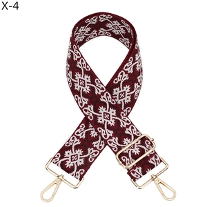 Détail de la bandoulière jacquard bordeaux avec mousquetons métalliques dorés