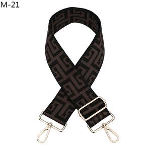 Macro detail of brown geometric maze pattern woven bag strap with gold metal buckles