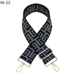 Close-up of adjustable geometric jacquard wide bag strap with gold metal hooks and buckle
