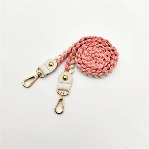 Macro detail of pink and white braided rope bag strap with gold metal lobster clasp hook