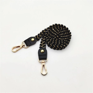 Detail of black and gold woven braided rope bag strap with gold lobster clasps