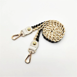 Detail of woven black and white rope strap with gold accents and leather connectors