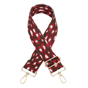 Adjustable leopard print bag strap with red spots and gold hardware on white background