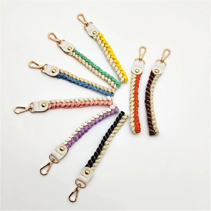 Close-up of colorful braided rope keychains with golden metal clasps and leather accents