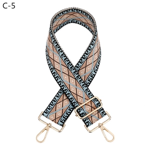 Detail of adjustable geometric jacquard bag strap with gold metal hooks and buckle