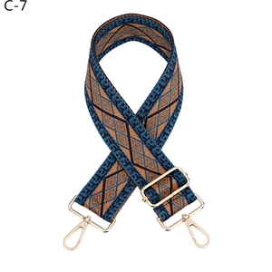 Close-up of wide woven shoulder strap with ethnic geometric pattern and gold clasps