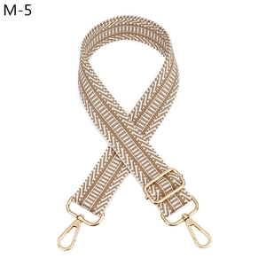 Détail d'une bandoulière en jacquard réglable avec crochets métalliques dorés