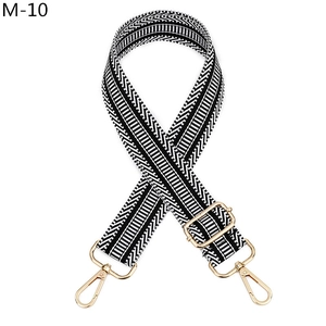 Détail d'une bandoulière réglable avec motif chevrons noir et blanc et boucles dorées