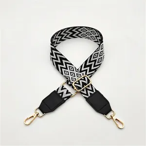 Detail of adjustable black and white geometric ethnic pattern strap with gold hooks