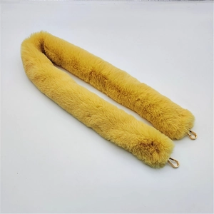 Macro view of bright yellow faux fur bag strap with polished gold metal lobster hooks