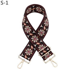 Detail of adjustable ethnic woven bag strap with red geometric patterns and gold hooks