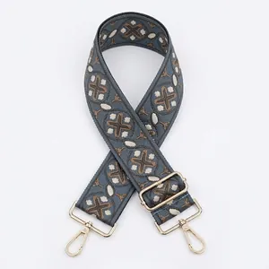 Close-up of geometric jacquard wide shoulder strap with gold-plated metal buckles