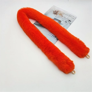 Detail of bright orange faux fur bag strap with gold lobster clasps on white background