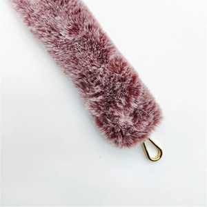 Detail of faux fox fur bag strap in purple and white with golden metal clasp