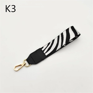 Detailed view of zebra print wrist strap with black leather and golden metal clasp
