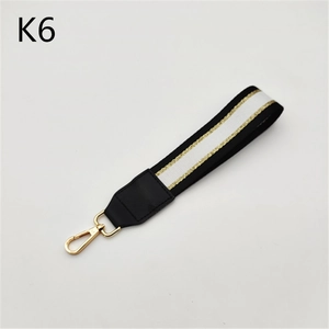 Detail of striped black and white bag wristlet strap with gold metal spring buckle